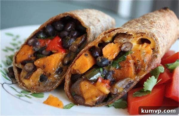 Two halves of a delicious sweet potato and black bean burrito, showcasing the rich, roasted vegetable filling and melted cheese, perfectly presented on a plate.