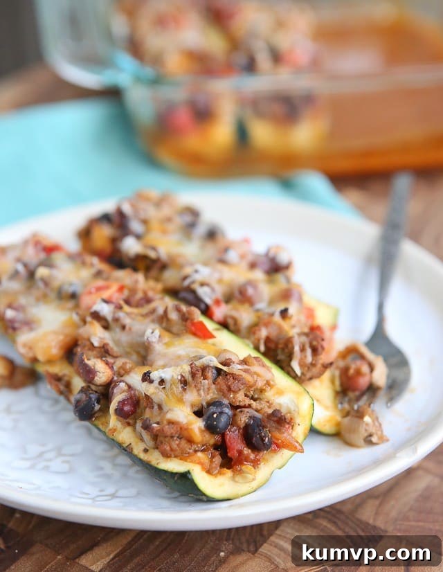 Easy Chili Stuffed Zucchini Boats: Perfect for leftover chili and healthy eating. Three Chili Stuffed Zucchini Boats topped with melted cheese, ready to serve. An easy, healthy, and low-carb dinner recipe.