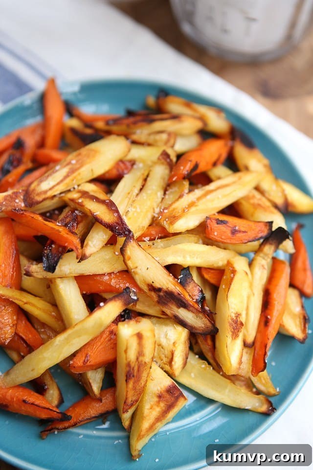 Delicious Honey Roasted Parsnips and Carrots Close-up of golden brown honey roasted parsnip and carrot sticks arranged on a blue plate, garnished with fresh herbs.