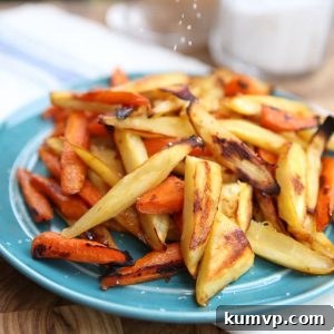 Close-up of golden brown honey roasted parsnip and carrot sticks on a white baking sheet, demonstrating their kid-friendly appeal.