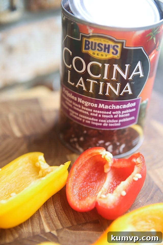 Close-up shot of Mini Mexican Stuffed Peppers, showcasing their rich filling of black refried beans, savory salsa, and golden-brown melted cheese, nestled in tender baby bell pepper halves.