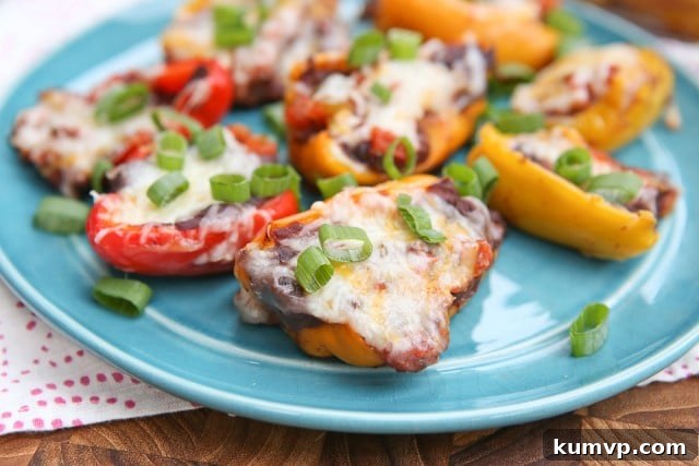 A vibrant platter of freshly baked Mini Mexican Stuffed Peppers, garnished with chopped green onions, ready to be served. The cheese topping is perfectly bubbly and golden, enhancing their visual appeal and deliciousness.