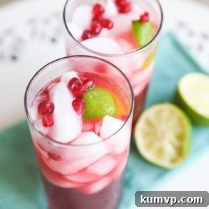 A vibrant Pomegranate Rum Cocktail garnished with lime and pomegranate arils, perfect for a festive occasion or a tropical escape.