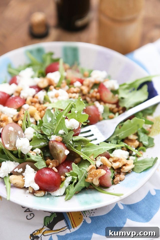 Close-up view of the Wheat Berry and Arugula Salad, showcasing the plump wheat berries, juicy grape halves, crumbled goat cheese, and fresh arugula leaves.
