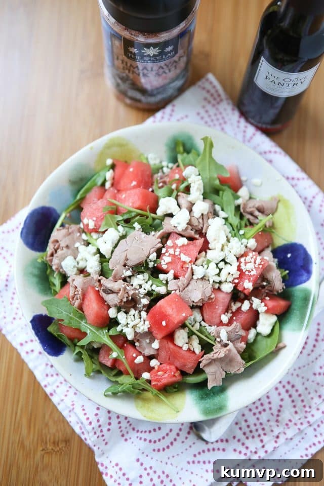 A vibrant bowl of Roast Beef, Spinach, and Arugula Salad with Watermelon, drizzled with a rich balsamic vinaigrette – a delightful and nutritious summer meal option.