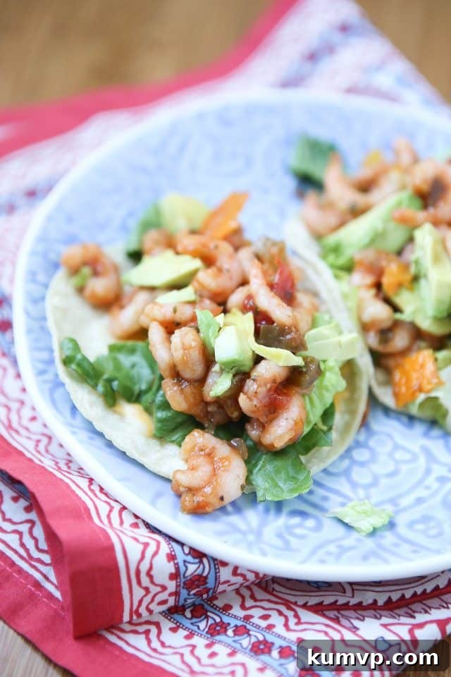 Mango Salsa Shrimp Tacos with Avocado Two soft corn tortillas generously stuffed with succulent shrimp, vibrant mango salsa, crisp lettuce, and creamy avocado slices, presented beautifully on a plate.