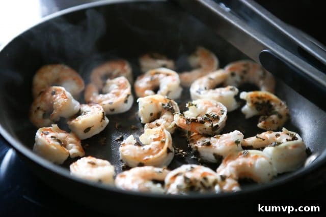 Sizzling Shrimp in a Skillet: A Quick Protein Boost Succulent shrimp seasoned with herbs and spices, sizzling in a nonstick skillet, indicating the beginning of a quick and flavorful dish.