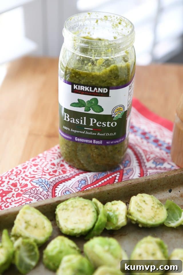 Crispy Pesto Brussels Sprouts 4 A vibrant green pesto being drizzled over fresh Brussels sprouts in a bowl, highlighting the key ingredients for this Italian-inspired roasted vegetable recipe via aggieskitchen.com