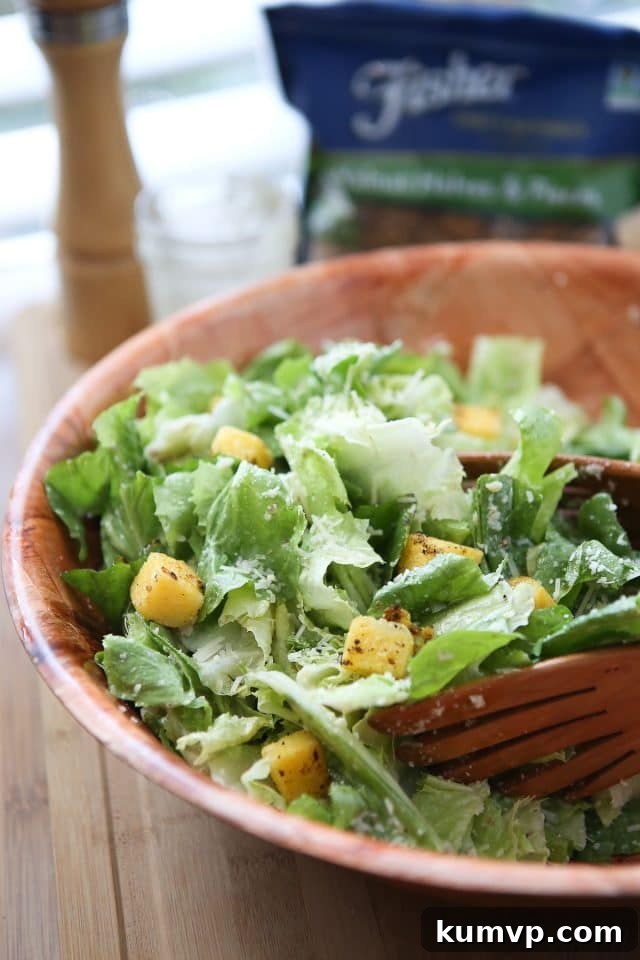 Large wooden bowl of caesar salad topped with polenta croutons and parmesan walnut lemon vinaigrette