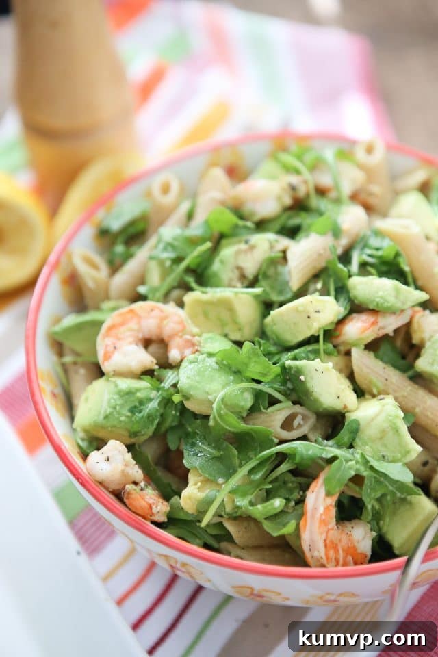 plate of whole wheat pasta topped with shrimp, arugula, and diced avocado