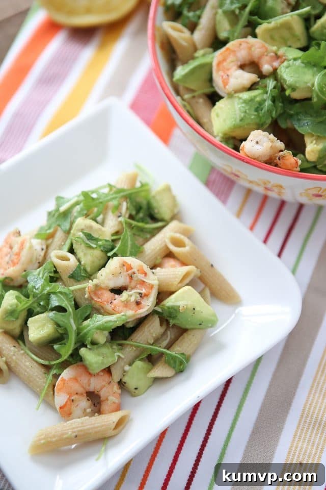 plate of whole wheat pasta topped with shrimp, arugula, and diced avocado