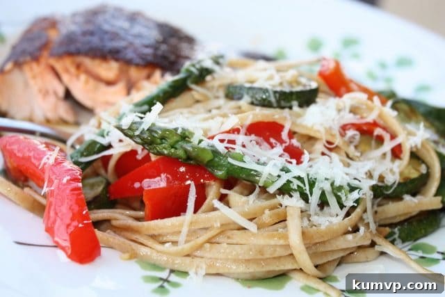 Wholesome Spring Vegetable Linguine 3 Close-up of Linguine with Spring Vegetables showing tender asparagus, sliced red peppers, and zucchini rounds glistening with olive oil and Parmesan cheese, intertwined with whole wheat pasta, ready to be served. A perfect healthy spring dinner or meatless meal.