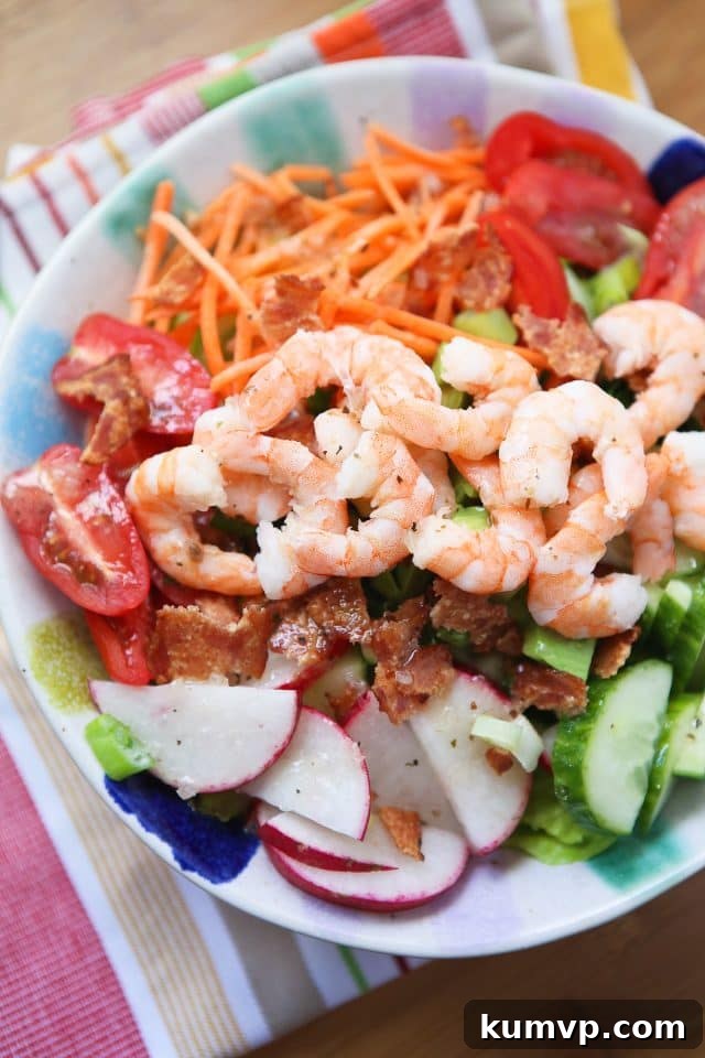 Garden Salad with Shrimp and Bacon A beautifully arranged bowl of garden greens, topped with perfectly cooked shrimp, shredded carrots, vibrant cherry tomatoes, crisp cucumber slices, thinly sliced radishes, and savory bacon bits, ready to be enjoyed.