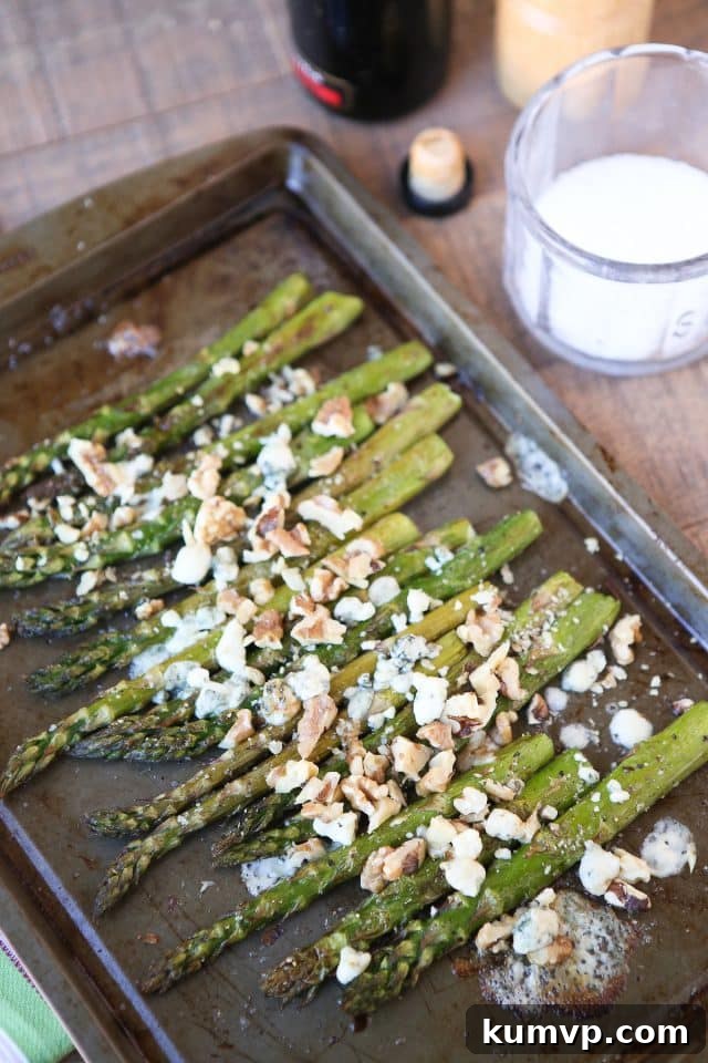 A large bunch of roasted asparagus with balsamic glaze, gorgonzola crumbles, and walnuts.