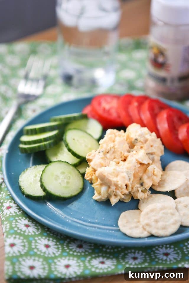 Creamy Greek Yogurt Egg Salad with smoked paprika, served with bread, crackers, and fresh vegetables for a healthy lunch or snack.