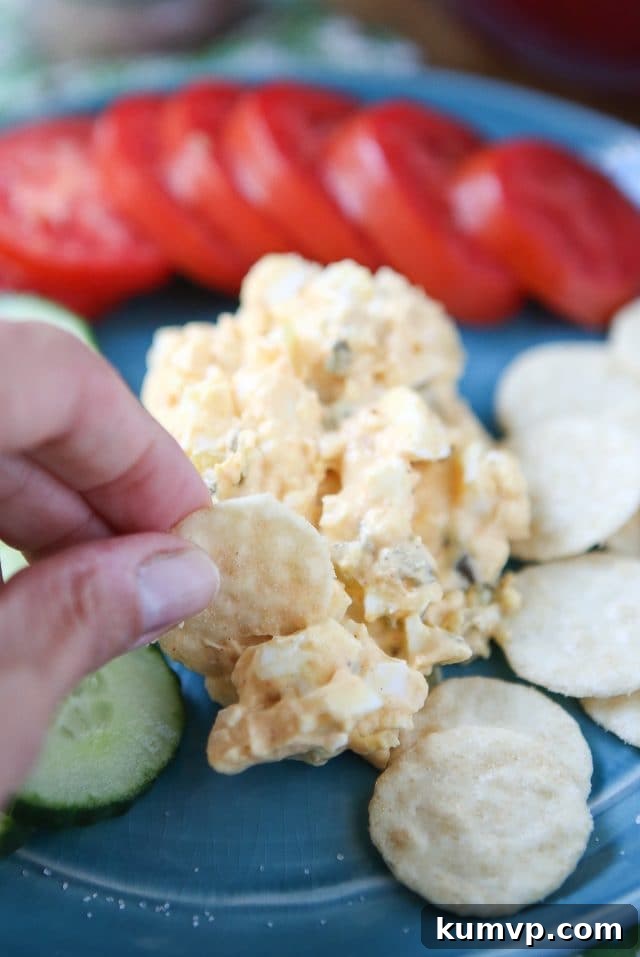 Creamy Greek Yogurt Egg Salad with smoked paprika served with fresh vegetables and rice crackers for a light meal.