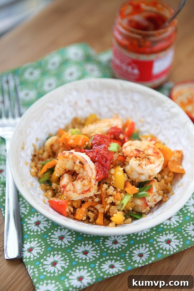 Quick lunch or dinner for one! Cajun Shrimp and Cauliflower Rice Stir Fry - low carb, high protein and full in flavor. A close-up of the stir fry, highlighting the rich colors and textures, with a dollop of spicy harissa on the side, ready to be mixed in.