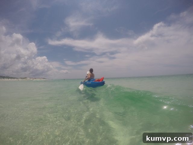 Kayaking on a Coastal Dune Lake, 30A An adult confidently kayaking on the calm, clear waters of a coastal dune lake, surrounded by lush vegetation, showcasing a peaceful activity.