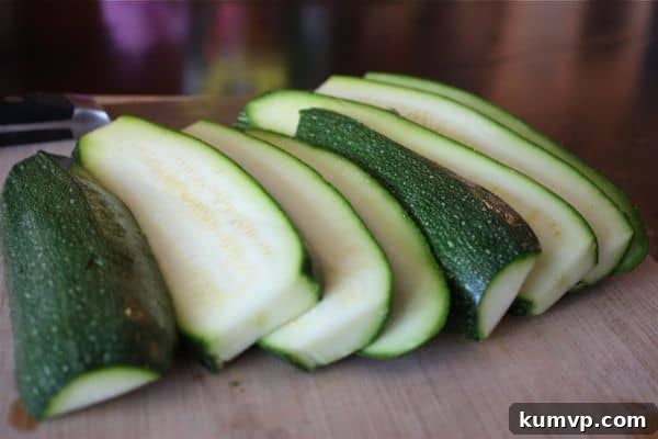 Crispy Parmesan Zucchini Fries 2 How to cut zucchini into sticks for baking, showing sliced zucchini planks on a cutting board.
