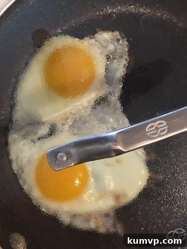 Gourmet Touch: Everything But The Bagel Seasoning Overhead view of a prepared Spinach and Egg Breakfast Toast, featuring a perfectly cooked egg on a bed of vibrant spinach, topped with seasoning, ready to be enjoyed. The whole-grain toast provides a sturdy base.