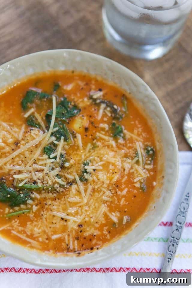 Comforting Tortellini Soup Meal with Water Overhead view of a comforting bowl of Tomato-Spinach Tortellini Soup, perfectly accompanied by a refreshing glass of water, illustrating a complete and satisfying meal setup on a rustic surface.