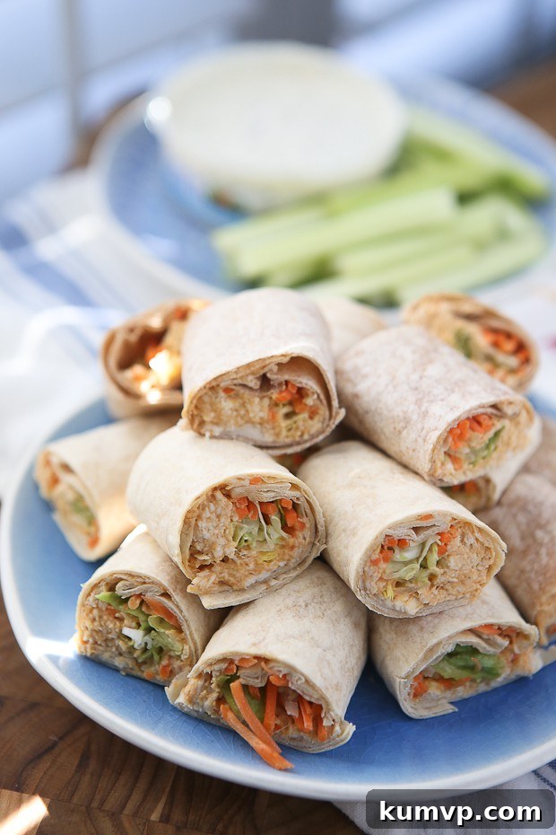 A platter of Buffalo Hummus Chicken Salad Roll Ups, featuring tender chicken salad mixed with buffalo sauce and hummus, rolled into tortillas and sliced into bite-sized pinwheels. A lightened-up, flavorful game day snack.