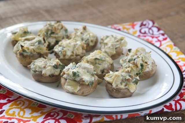 Delicious artichoke stuffed mushrooms, beautifully baked and presented, highlighting a savory and cheesy filling within tender mushroom caps. A perfect vegetarian appetizer for any gathering.