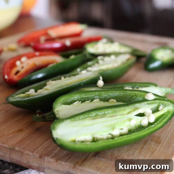 Preparing Jalapenos for Stuffing Fresh jalapenos sliced in half lengthwise, with seeds and membranes clearly visible, ready for cleaning and stuffing.