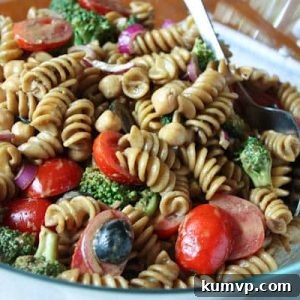 Pasta salad with cherry tomatoes, olives, red onions, and broccoli in a bowl