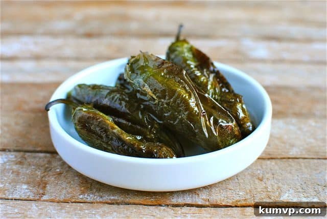 Roasted Jalapeno Peppers for the Spicy Shrimp Marinade Base Four perfectly roasted jalapeño peppers with charred skins, resting in a small, rustic white bowl. These peppers are central to creating the spicy and complex flavor profile of the shrimp marinade.