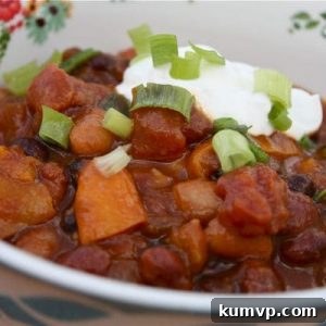 A close-up of a bowl of comforting Slow Cooker 3-Bean Pumpkin Chili, garnished and ready to eat.