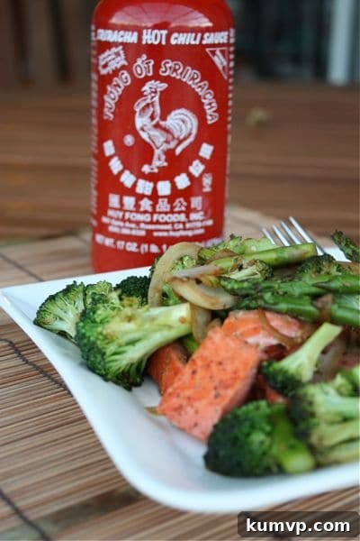 Salmon and Veggie Stir Fry A beautifully plated salmon and veggie stir fry, with a bottle of sriracha hot sauce subtly blurred in the background, suggesting a customizable spice level.