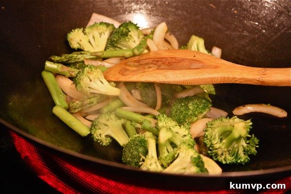 Salmon and Veggie Stir Fry A wok filled with fresh vegetables like broccoli, asparagus, and sliced sweet onions, being stir-fried to crisp-tender perfection.