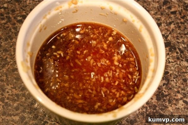 Salmon and Veggie Stir Fry A small bowl holding the essential Asian seasoning mix for stir fry: soy sauce, rice vinegar, grated ginger, and minced garlic.