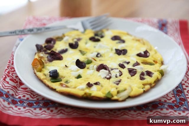 Mediterranean Feta Frittata with Peppers and Onions 5 Close-up of a Greek Pepper and Onion Frittata cooked in a small skillet, showing the perfectly browned top with melted feta cheese and visible pieces of peppers and onions, ready to be served directly from the pan.