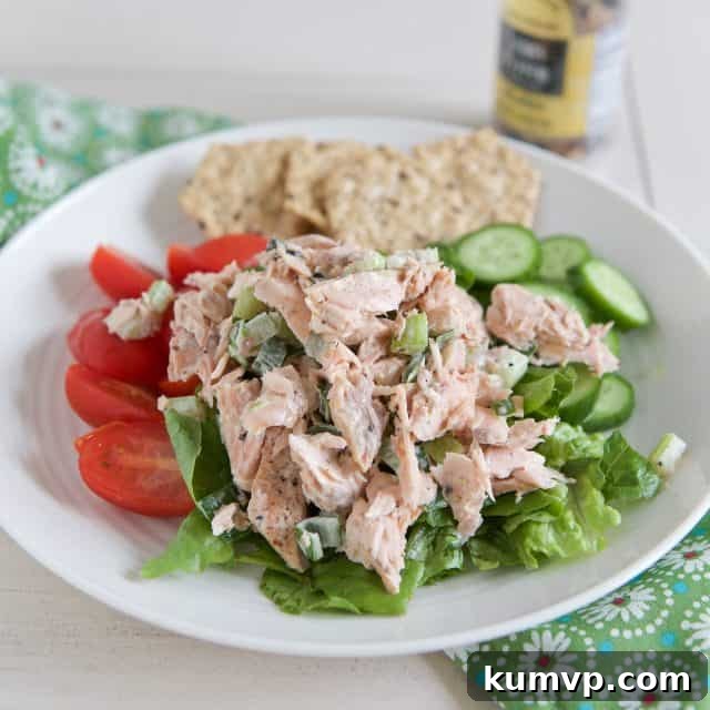 Flaked Salmon Salad Delight 2 white plate filled with lettuce tomato cucumbers topped with creamy salad salad with crackers