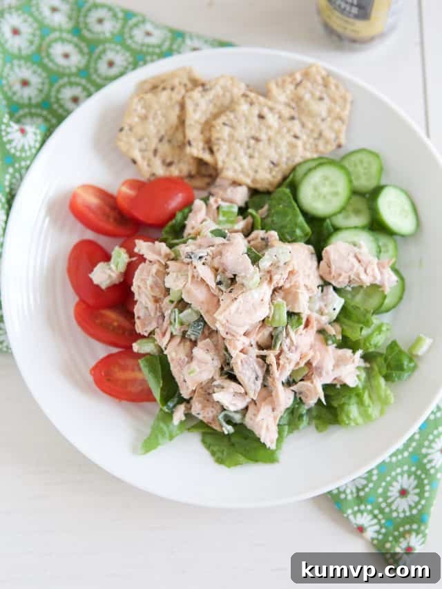 Flaked Salmon Salad Delight 3 white plate filled with lettuce, tomato and cucumber topped with salmon salad and crackers on side
