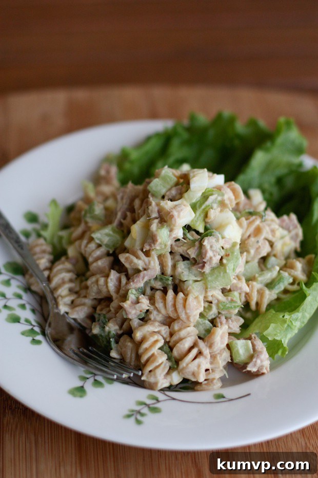 Healthy Greek Yogurt Tuna Pasta Salad for Quick Lunches and Dinners A vibrant bowl of creamy tuna pasta salad with whole grain pasta, celery, and hard-boiled eggs, garnished with fresh parsley.