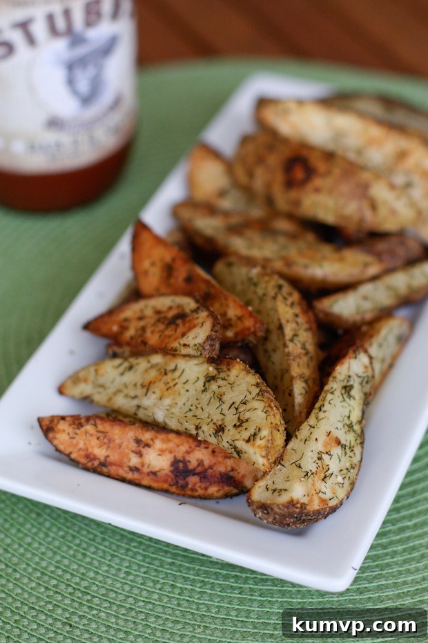 Oven Roasted Potato Wedges with Dill make a great side dish to your burgers all summer long. Easy to make and always enjoyed by all. recipe via AggiesKitchen.com #potatoes #sidedish #vegetable #potato #roasted #frenchfries oven roasted potato wedges with dill on a white rectangle serving plate