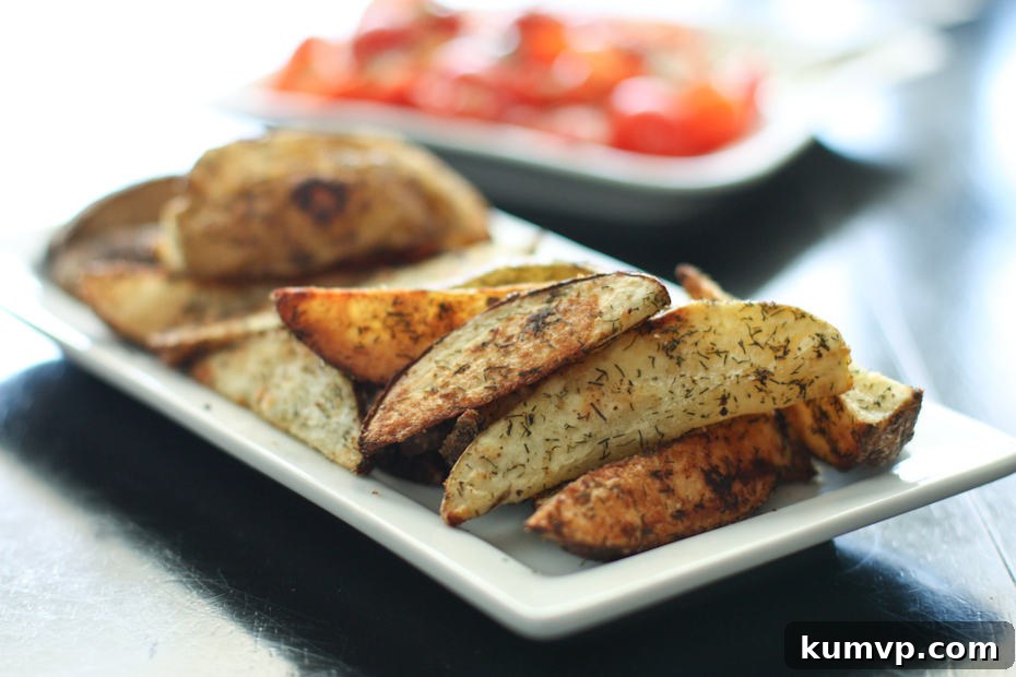 Oven Roasted Potato Wedges with Dill make a great side dish to your burgers all summer long. Easy to make and ready in 30 minutes! #potatoes #dill #roasted #frenchfries #potatorecipe #sidedish #vegetable oven roasted potato wedges with dill on white rectangle plate