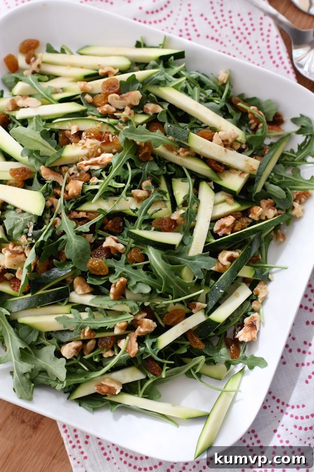 plate of arugula salad topped with walnuts and zucchini strips