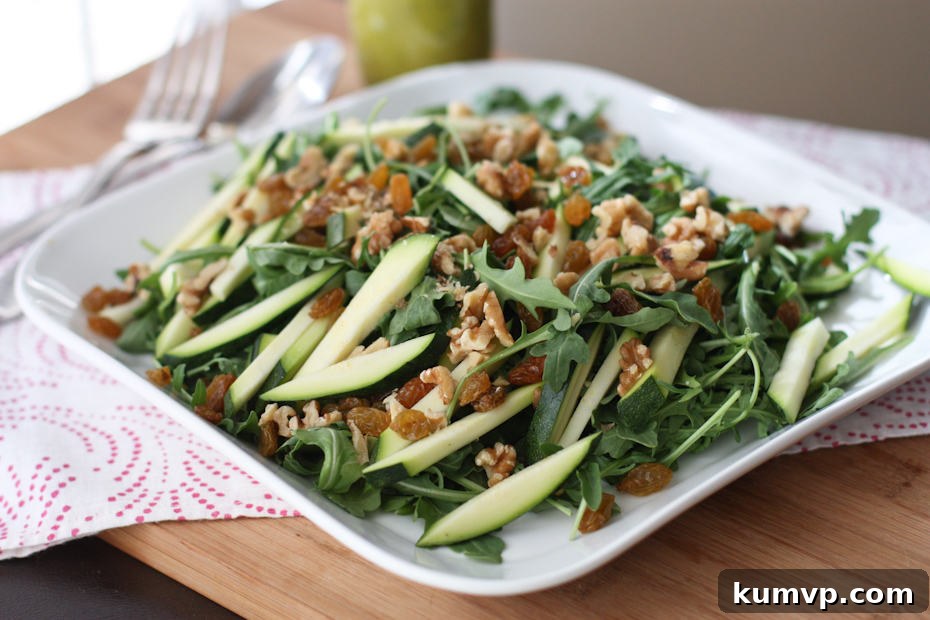 plate of arugula salad topped with walnuts and zucchini strips