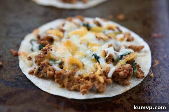 Close-up of a baked tostada with turkey, spinach, and melted cheese