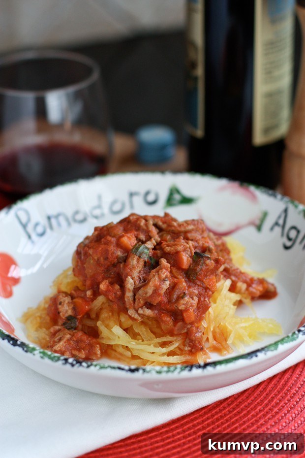 Bowl of shredded spaghetti squash topped with rich ground turkey and red bolognese sauce, garnished with fresh herbs.