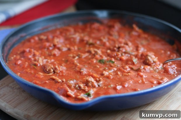 Close-up of turkey bolognese sauce simmering in a large skillet, rich and inviting.