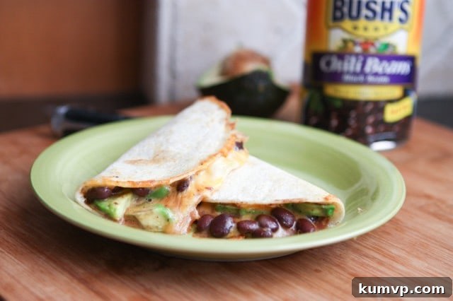 A plate of perfectly cooked Black Chili Bean and Avocado Quesadillas, garnished with fresh cilantro, ready for serving.