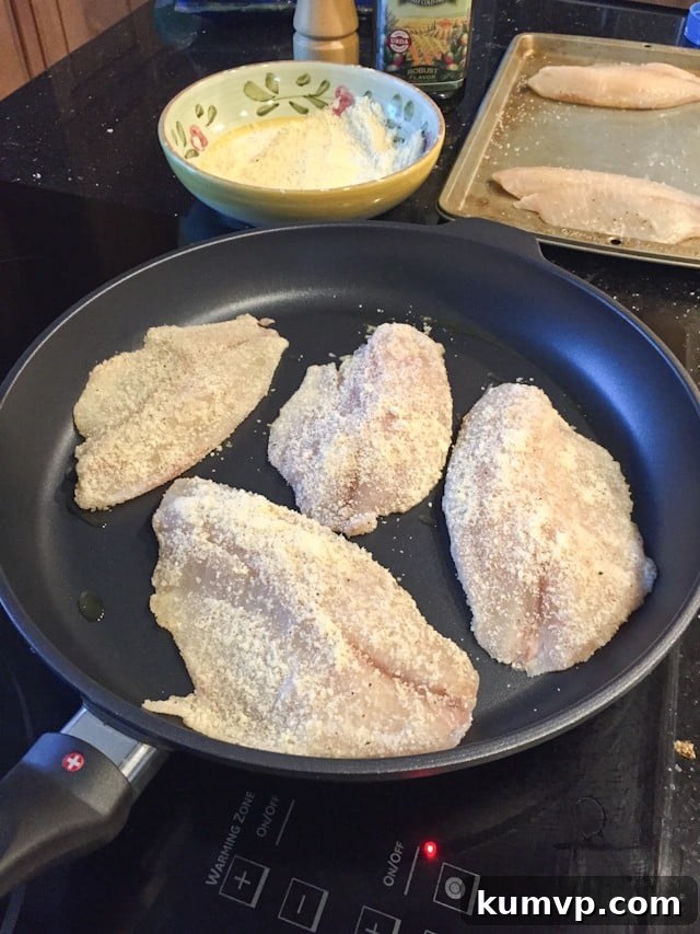 parmesan crusted fish cooking in skillet
