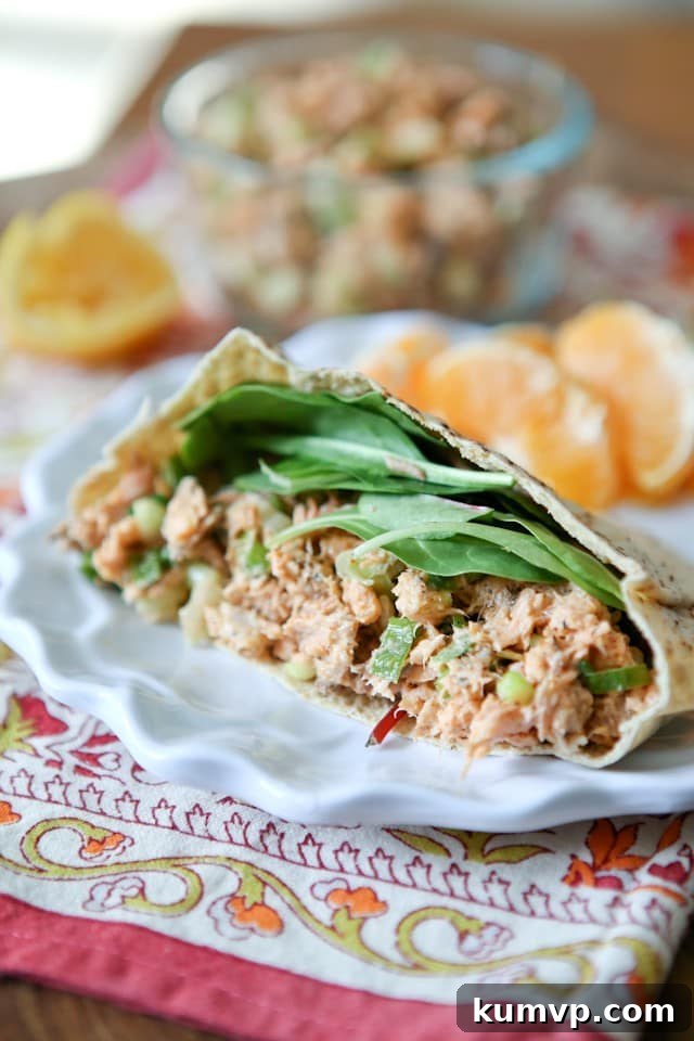 Blackened Salmon Salad Half of a pita stuffed with rich blackened salmon salad and fresh spinach leaves, ready for a healthy meal.