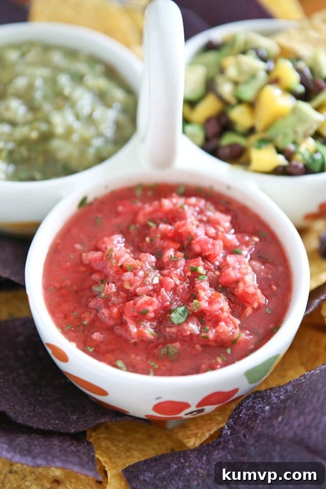 A vibrant bowl of freshly made tomato salsa, perfect for dipping tortilla chips. It's a restaurant-style salsa with a rich red color and visible chunks of fresh ingredients like tomatoes, onions, and cilantro.