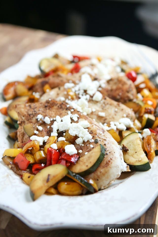 A vibrant plate of Skillet Balsamic Chicken with Sweet Peppers and Zucchini, garnished with fresh corn and crumbled feta cheese, ready to be enjoyed as a healthy and quick summer dinner.
